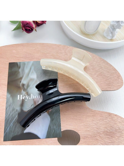 Pastel curved claw clip held in hand demonstrating size and grip