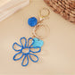 Raffia keychain hanging from a bag strap outdoors with blurred background