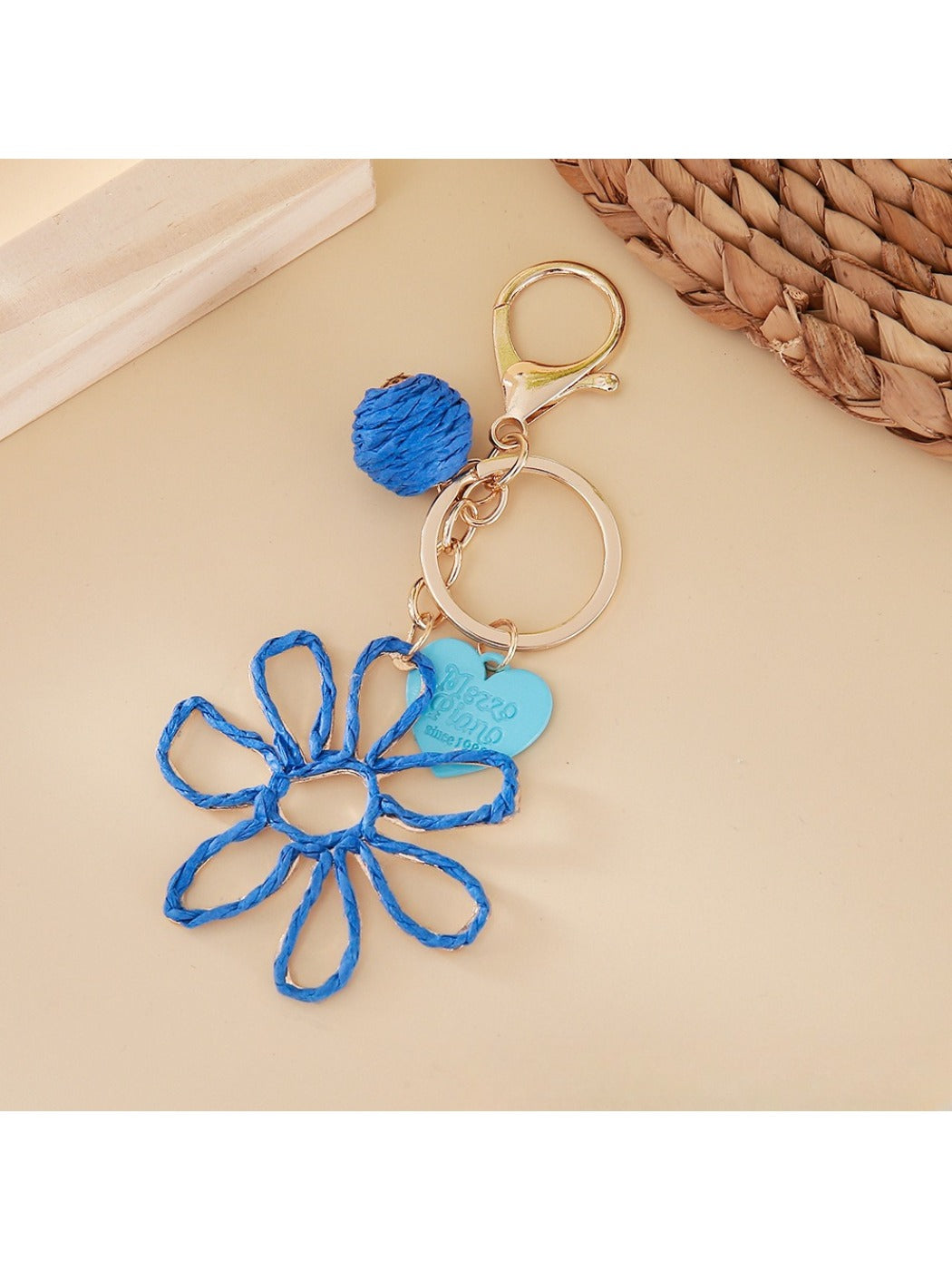 Raffia keychain hanging from a bag strap outdoors with blurred background