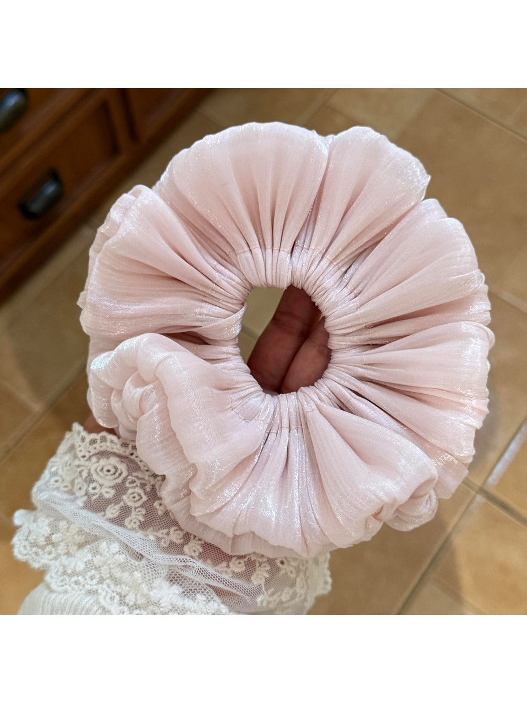 Side view of a ruched satin scrunchie highlighting its elasticity