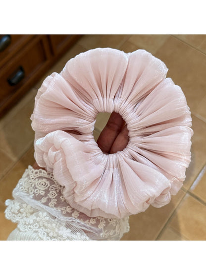 Side view of a ruched satin scrunchie highlighting its elasticity