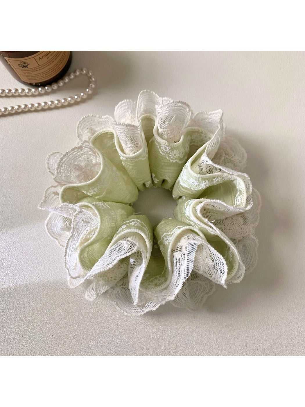 Close-up of green lace scrunchie showing delicate fabric texture and design