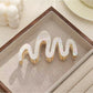 Beau wavy hair clip in silver finish displayed against a dark background
