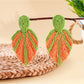 Earedge raffia woven leaf shaped earrings next to green leaves for styling