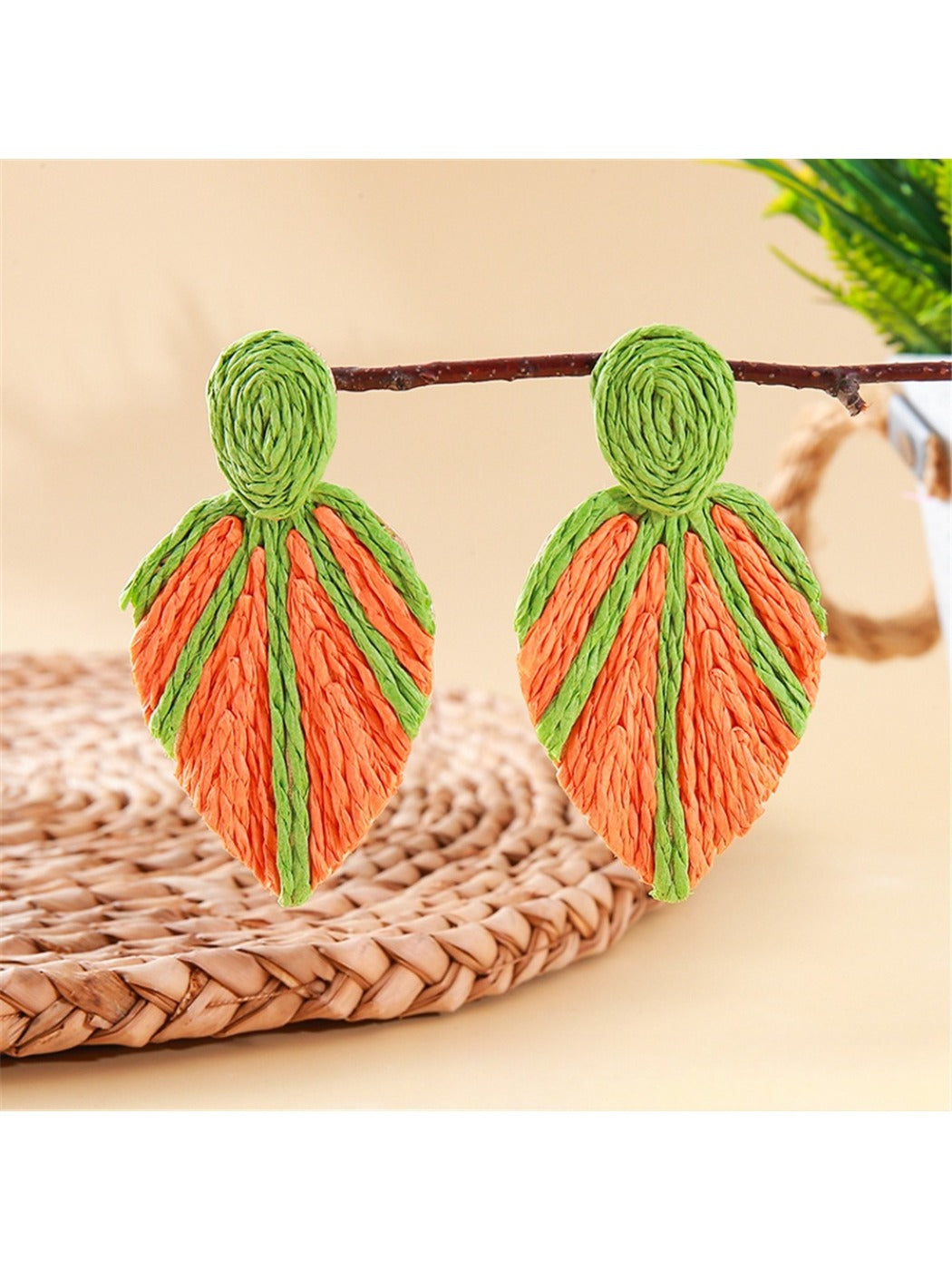 Earedge raffia woven leaf shaped earrings next to green leaves for styling