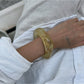 Lovra irregular shaped bangle bracelet resting on a neutral fabric background