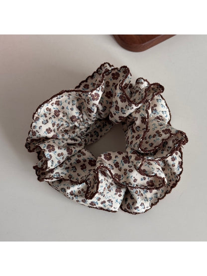 Flat lay of Gifty Retro Lace Floral Scrunchie alongside matching accessories on beige cloth