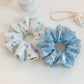 Close-up of blue fabric scrunchie featuring white bow patterns