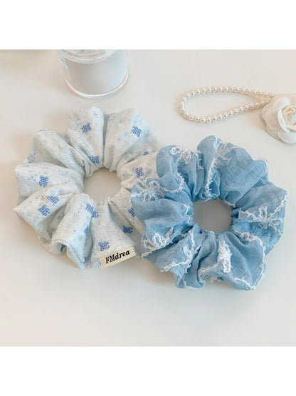Close-up of blue fabric scrunchie featuring white bow patterns