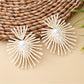 Earedge raffia drop earrings placed next to green leaves for natural aesthetic