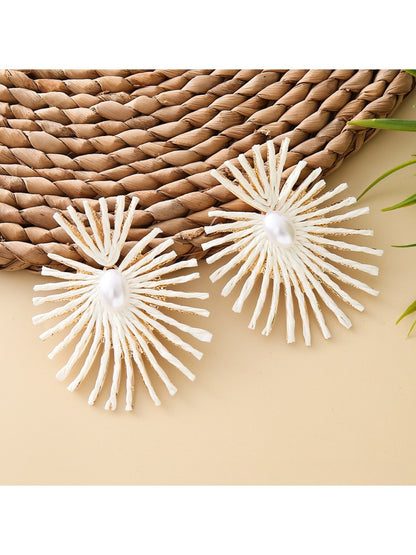 Earedge raffia drop earrings placed next to green leaves for natural aesthetic