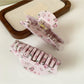 Beau hair claw clip held in hand showing size and rose print details