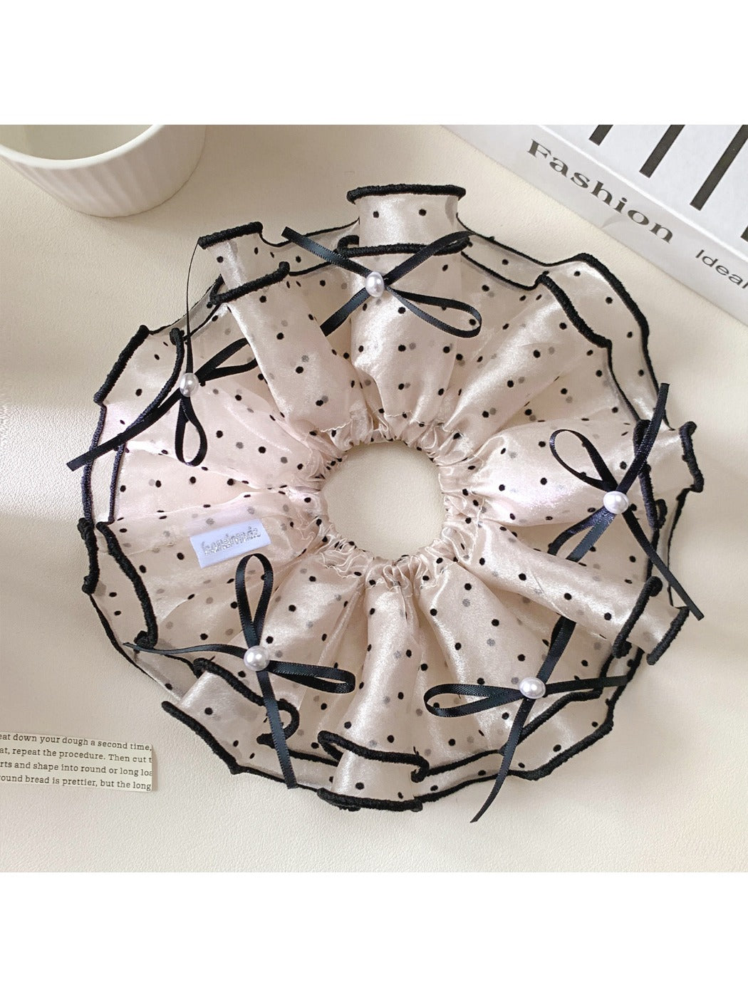 Close-up of Gifty satin polka dot bow scrunchie in black with white dots