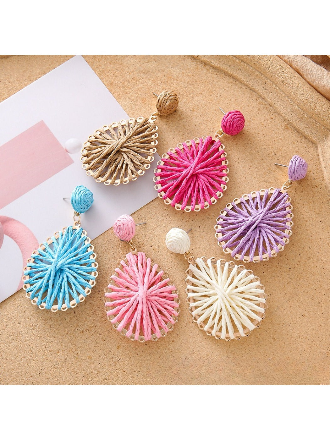 Close-up of Earedge stylish raffia teardrop shaped earrings on white background
