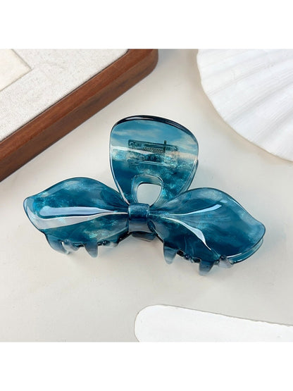 Top view of iridescent bow hair claw clip with light reflections