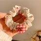 Close-up of Gifty Sweet Plaid Cherry Hair Tie with red and white plaid pattern and cherry charm
