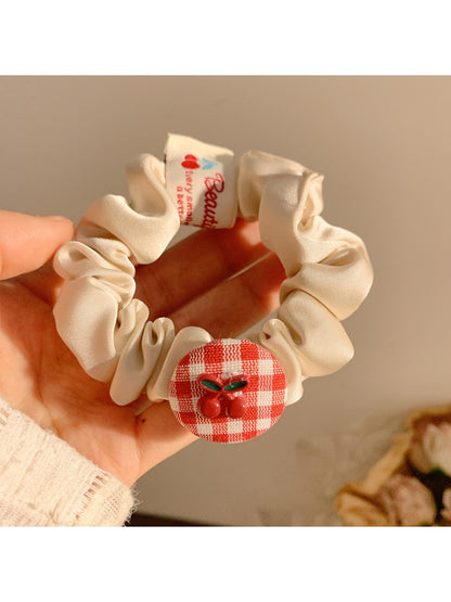 Close-up of Gifty Sweet Plaid Cherry Hair Tie with red and white plaid pattern and cherry charm