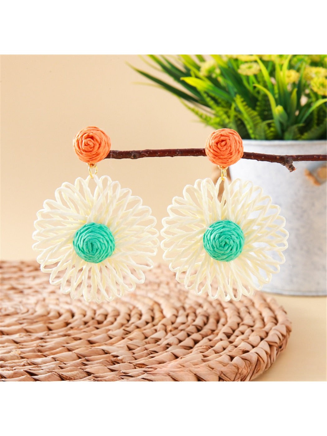 Earedge raffia flower shaped drop earrings worn on a model's ear