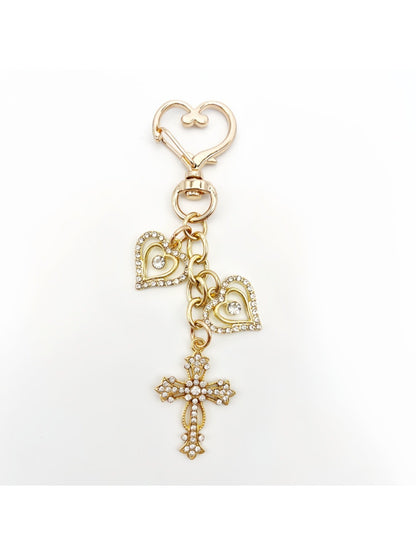 Keychain with vintage cross pendant held in a hand for scale
