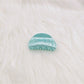 Beau claw clip resting on fabric with marble pattern details visible
