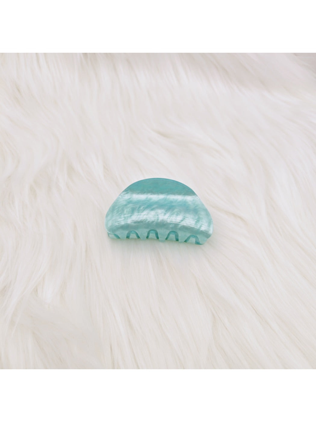 Beau claw clip resting on fabric with marble pattern details visible