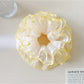 Misty blue polka dot scrunchie displayed on a wooden surface