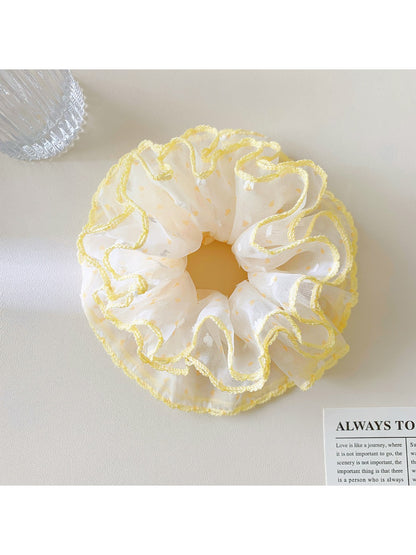 Misty blue polka dot scrunchie displayed on a wooden surface