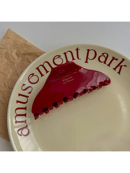 Top view of Beau red acetate hair clip displaying smooth surface and clasp