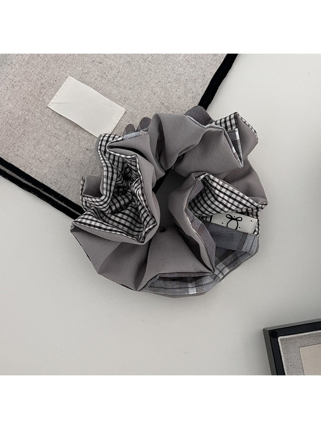 Gifty scrunchie worn on a wrist, highlighting its colorful plaid patchwork design