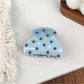 Blue polka dot hair claw clip with curved design and clasp