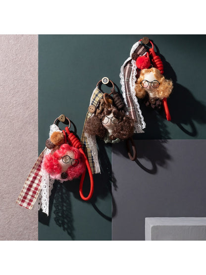 Close-up of fabric doll keychain showing detailed curly hair and embroidered features