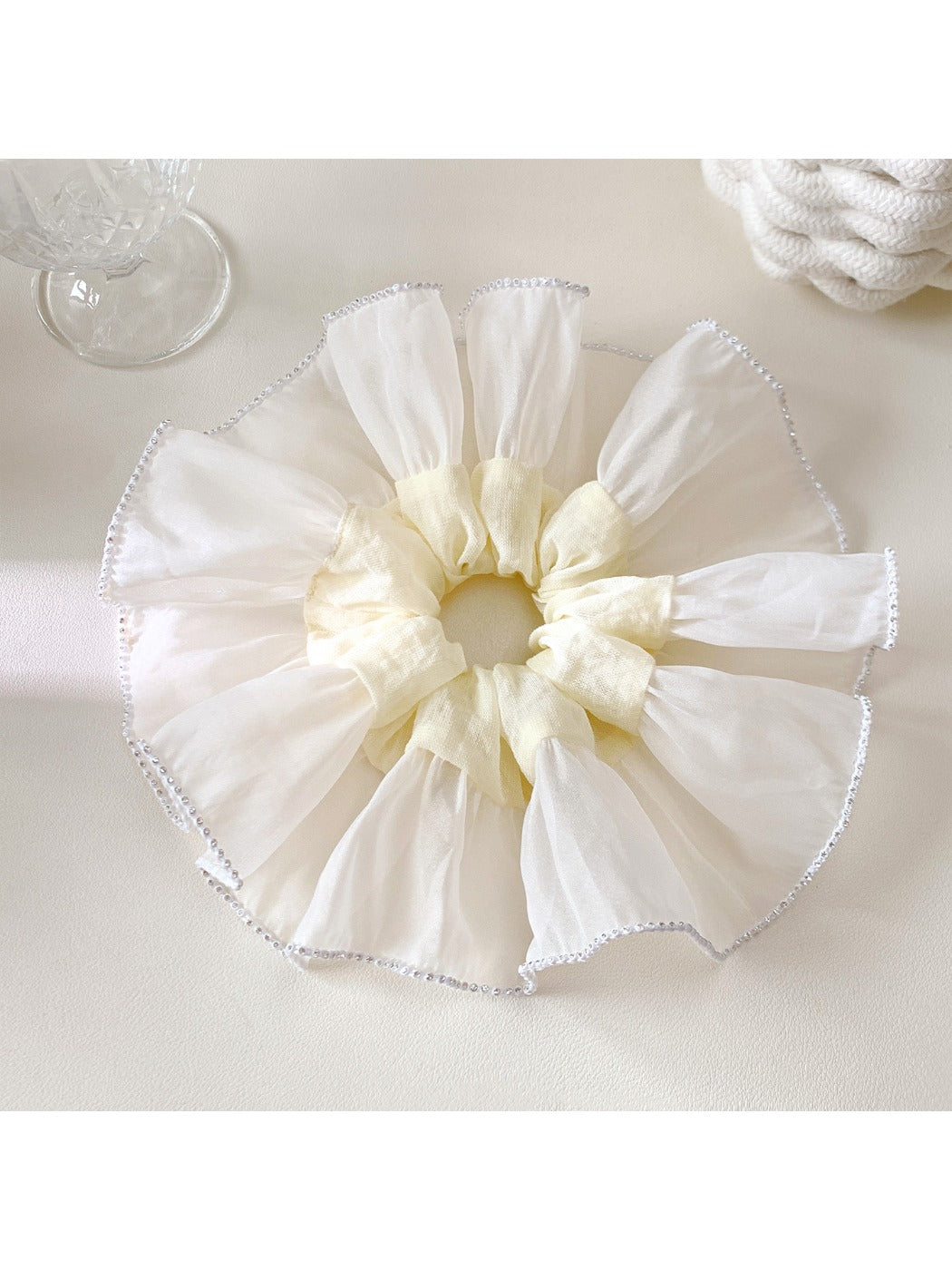 Close-up of white silky scrunchie showing soft fabric and gathered elastic design