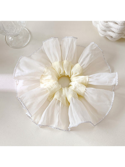 Close-up of white silky scrunchie showing soft fabric and gathered elastic design