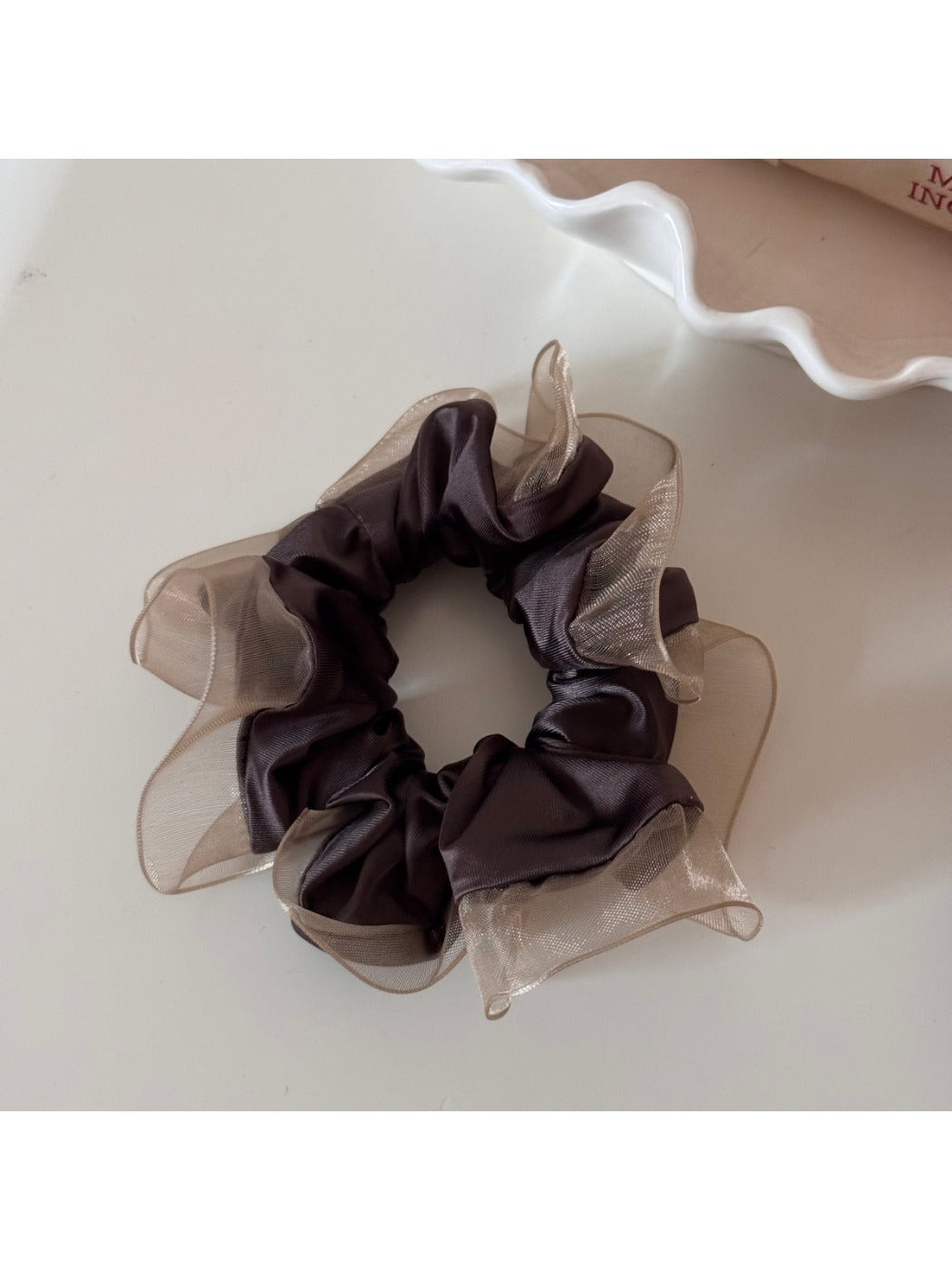 Glossy scrunchie displayed on a white background highlighting its shine