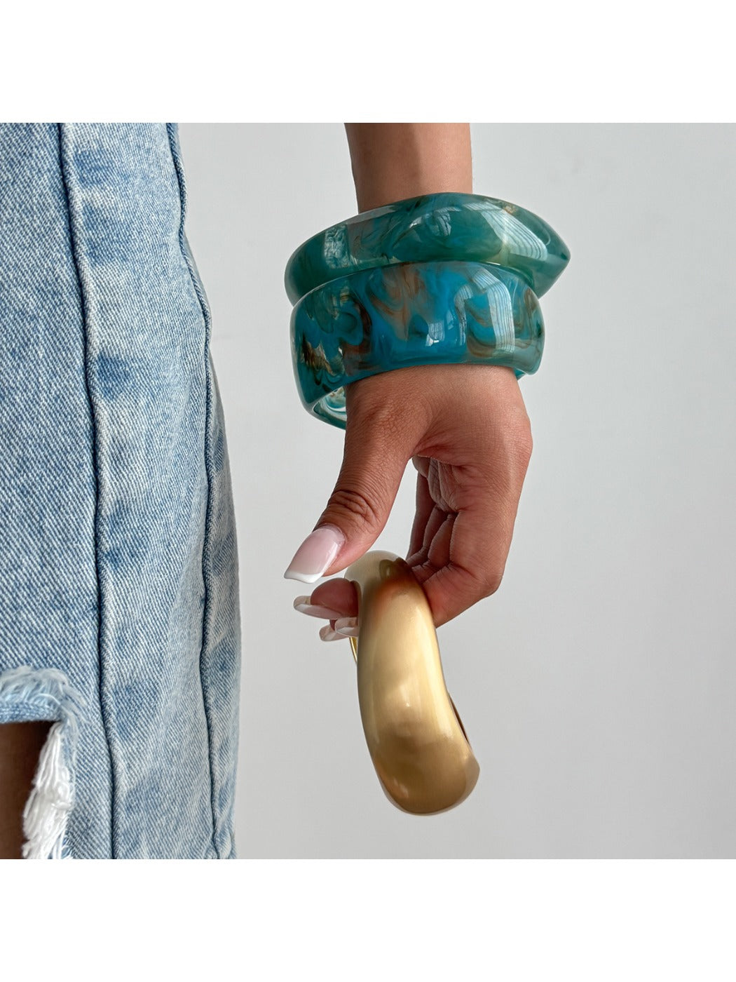 Lovra irregular textured silver bracelet worn on model's wrist with neutral outfit