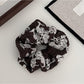 Gifty scrunchie styled with casual outfit on a wooden surface
