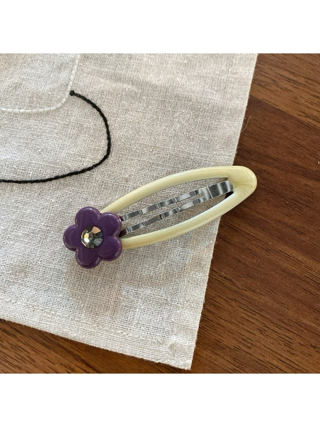 Beau flower pattern hair clip held in hand showing size and design