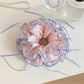 Pink fabric scrunchie with a bow print on a white background