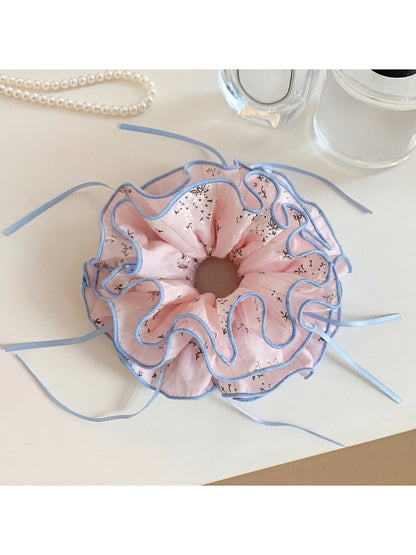 Pink fabric scrunchie with a bow print on a white background