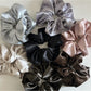 Close-up of Gifty solid lustrous satin scrunchie in soft pink on white background