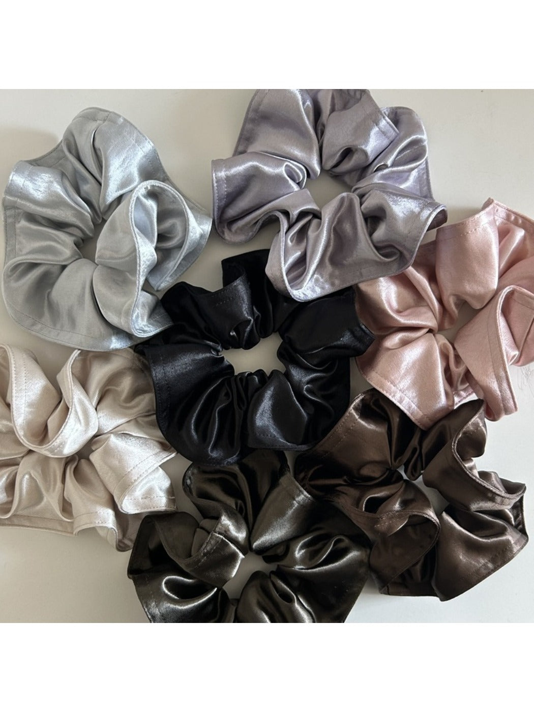 Close-up of Gifty solid lustrous satin scrunchie in soft pink on white background