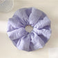 Scrunchie wrapped around a ponytail, showcasing its vibrant colors and soft fabric