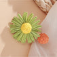 Beau raffia woven strawberry flower hair clip with visible green leaves detail