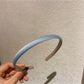 Candy color satin headband in pastel blue shown on white surface