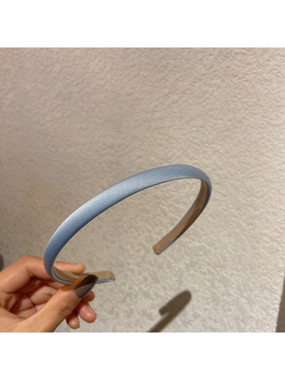 Candy color satin headband in pastel blue shown on white surface