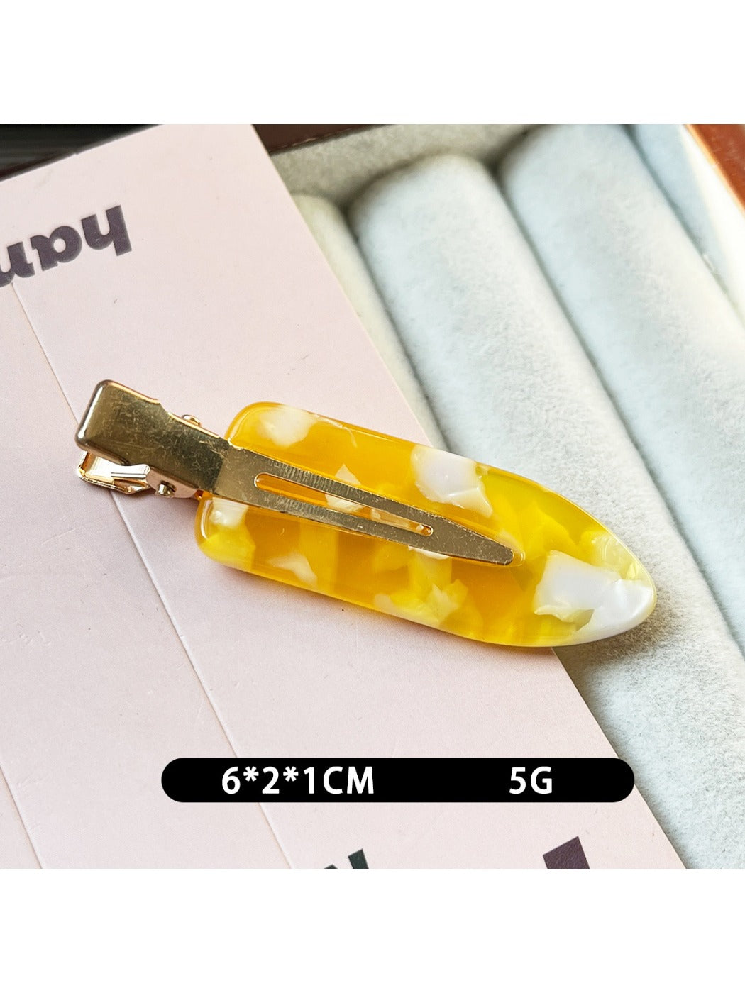 Beau acetate invisible hair clip resting on a wooden surface