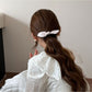 Gifty plaid hair tie with red bow shown from a side angle on a white surface