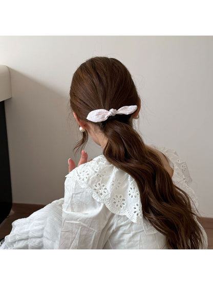 Gifty plaid hair tie with red bow shown from a side angle on a white surface