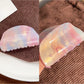 Beau colorful hair claw clip resting on fabric background
