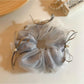 Close-up of Gifty tulle ribbon bow scrunchie in soft pink on white background